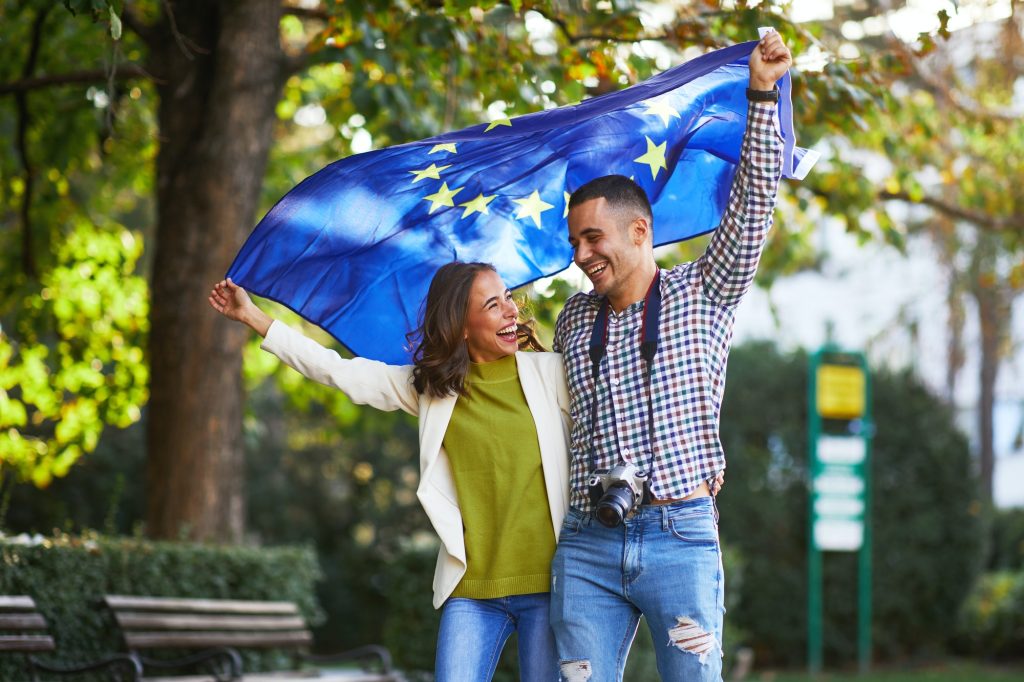 Happy young couple of tourists with a European Union flag